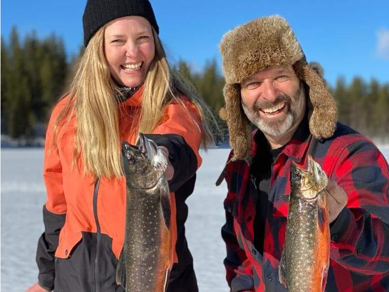 Frau und Mann mit gefangenen Fisch beim Eisangeln.