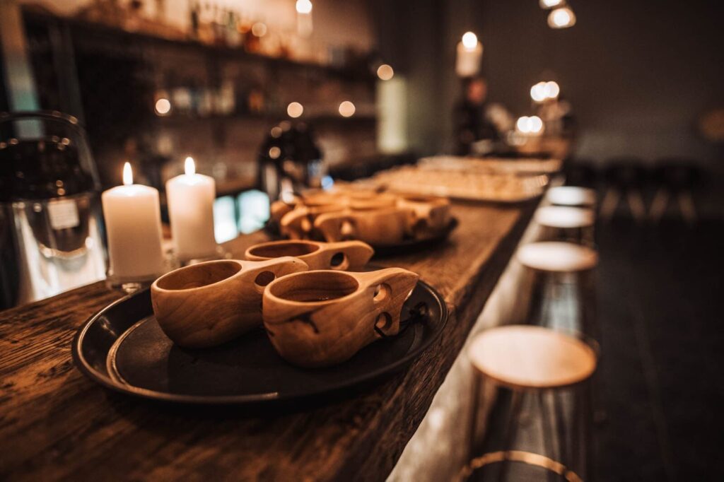 Kerzenschein an der Bar mit Holztassen.