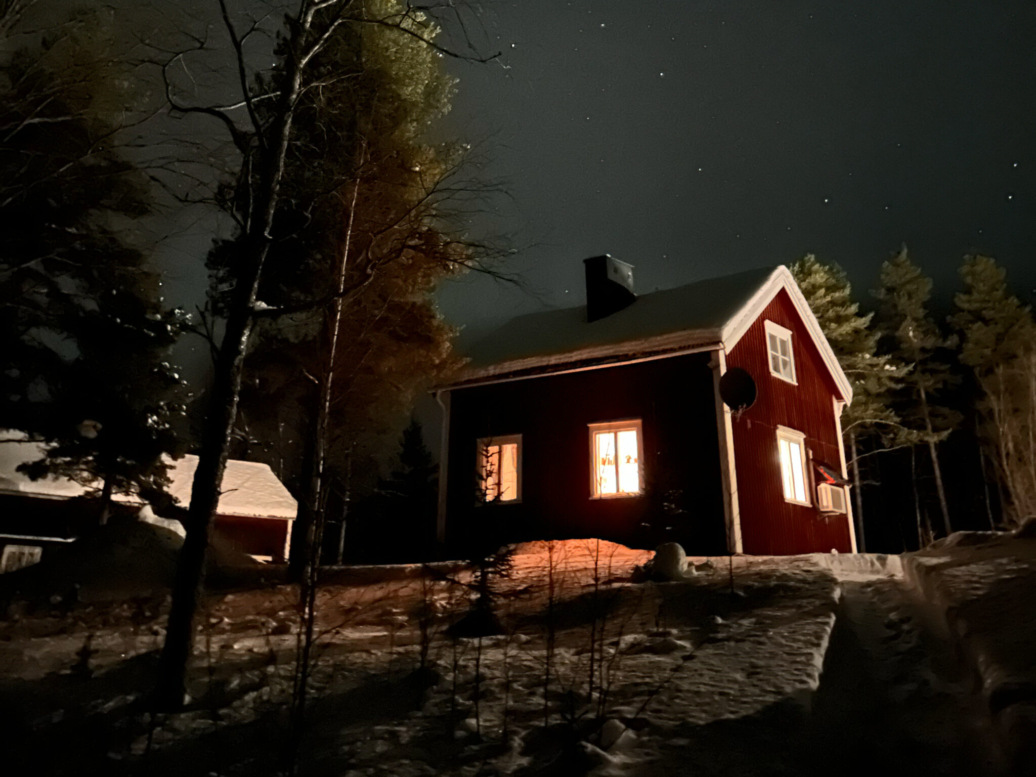 kleines rotes Schwedenhaus im Winterwoderland bei Nacht.